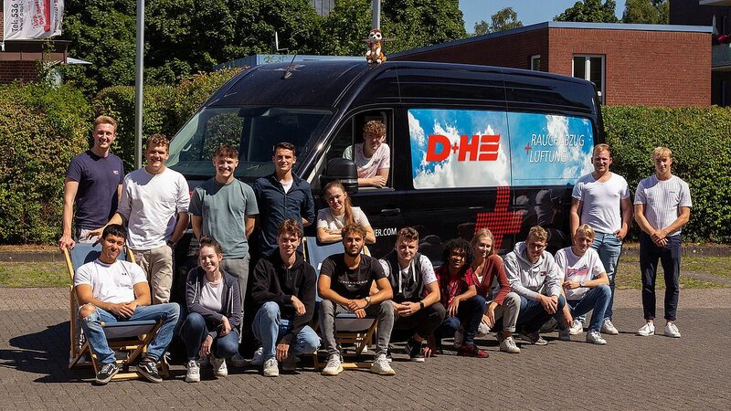 The trainees stand in front of the large D+H company bus