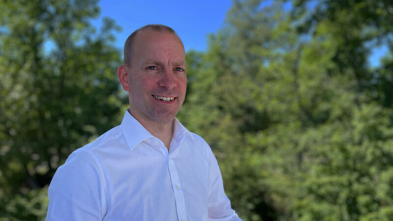 Head of indoor sales, Sven Leisering, standing outside in nature and smiling 