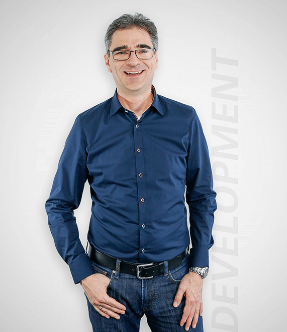 Development Department, Norbert Leufen, stands in the office and smiles
