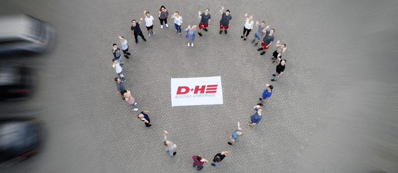 An aerial view of 25 colleagues or trainers of the year are set up in a heart shape, with a D+H logo in the middle.